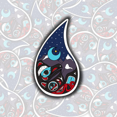 Sticker is shaped like a raindrop. Inside raindrop are mountains, the moon and stars, and a raven at the bottom of the raindrop. 